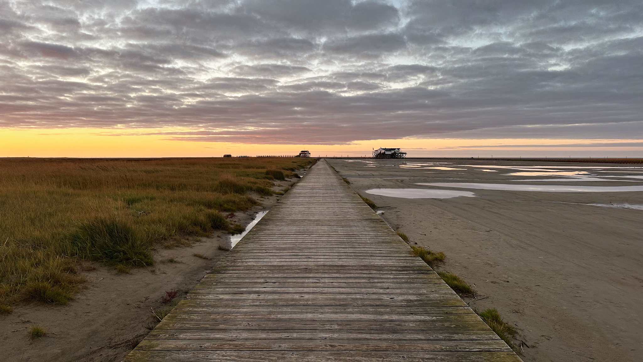 Blick auf einen langen Holzsteg an einem Strand